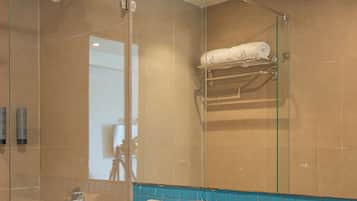 Et moderne badeværelse med en glasbrusekabine, et hvidt toilet, en vask med sort bordplade og en backsplash med blå fliser.