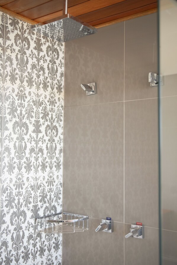 A bathroom with patterned wallpaper, a shower area, and a glass partition.