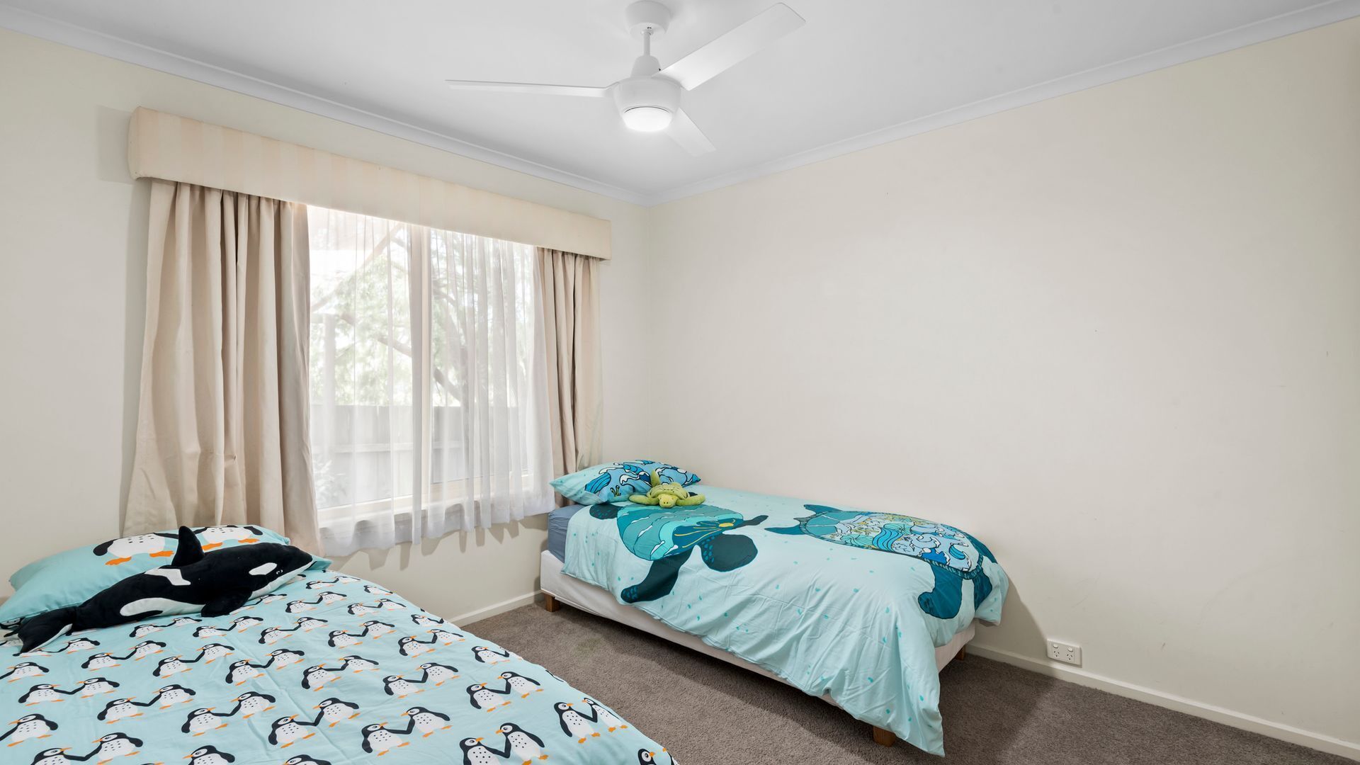 Ein Schlafzimmer mit zwei Betten, einem Deckenventilator und einem Fenster mit Vorhängen.