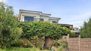 Ein zweistöckiges Haus mit überdachter Terrasse und Holzzaun.