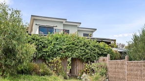 Ein zweistöckiges Haus mit überdachter Terrasse und Holzzaun.