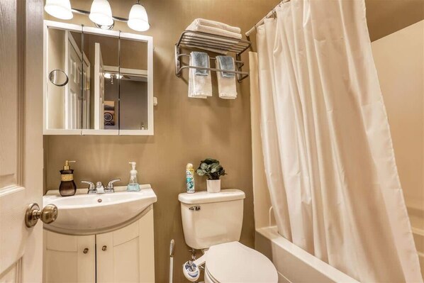 A bathroom with a sink, toilet, and a shower curtain.