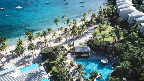 Un resort con una grande piscina, palme e una spiaggia.