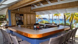 Angolo bar con vista sull'oceano, sgabelli da bar e un bancone.