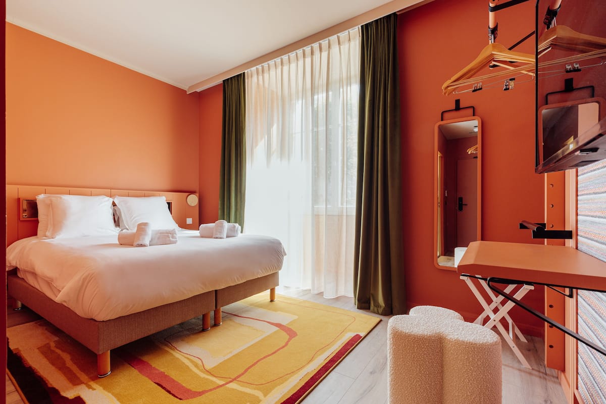 Ein Hotelzimmer mit einem Bett, einem Schreibtisch, einem Spiegel und einem Fernseher.