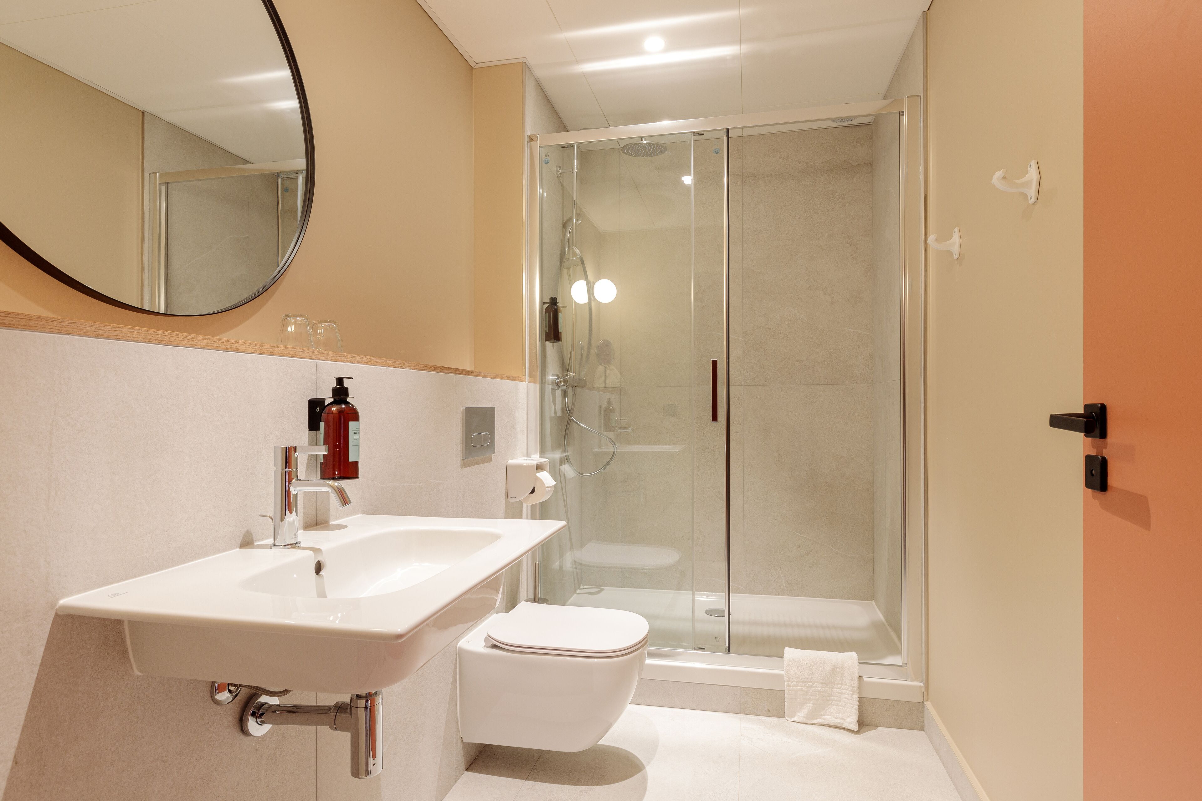 A modern bathroom with a white sink, toilet, and glass-enclosed shower.