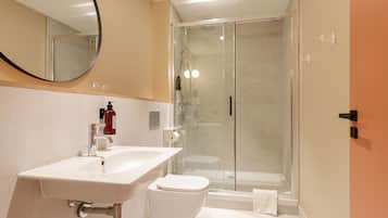 A modern bathroom with a white sink, toilet, and glass-enclosed shower.