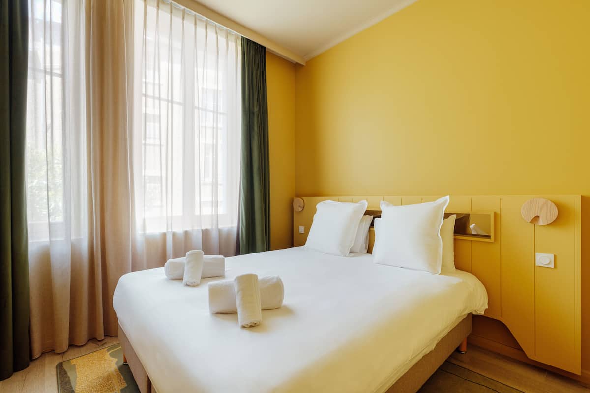 Ein Hotelzimmer mit einem großen Bett, weißen Leinen und einem Holzkopfbrett.