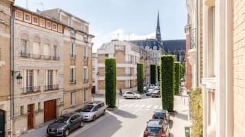 A street view with buildings, parked cars, and a church spire in the background.
