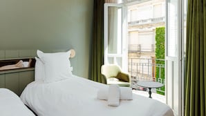Una habitación de hotel con cama, una silla y una mesita de noche junto a un ventanal grande.
