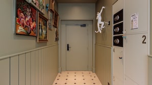 Un pasillo con taquillas, una puerta y obras de arte en las paredes.