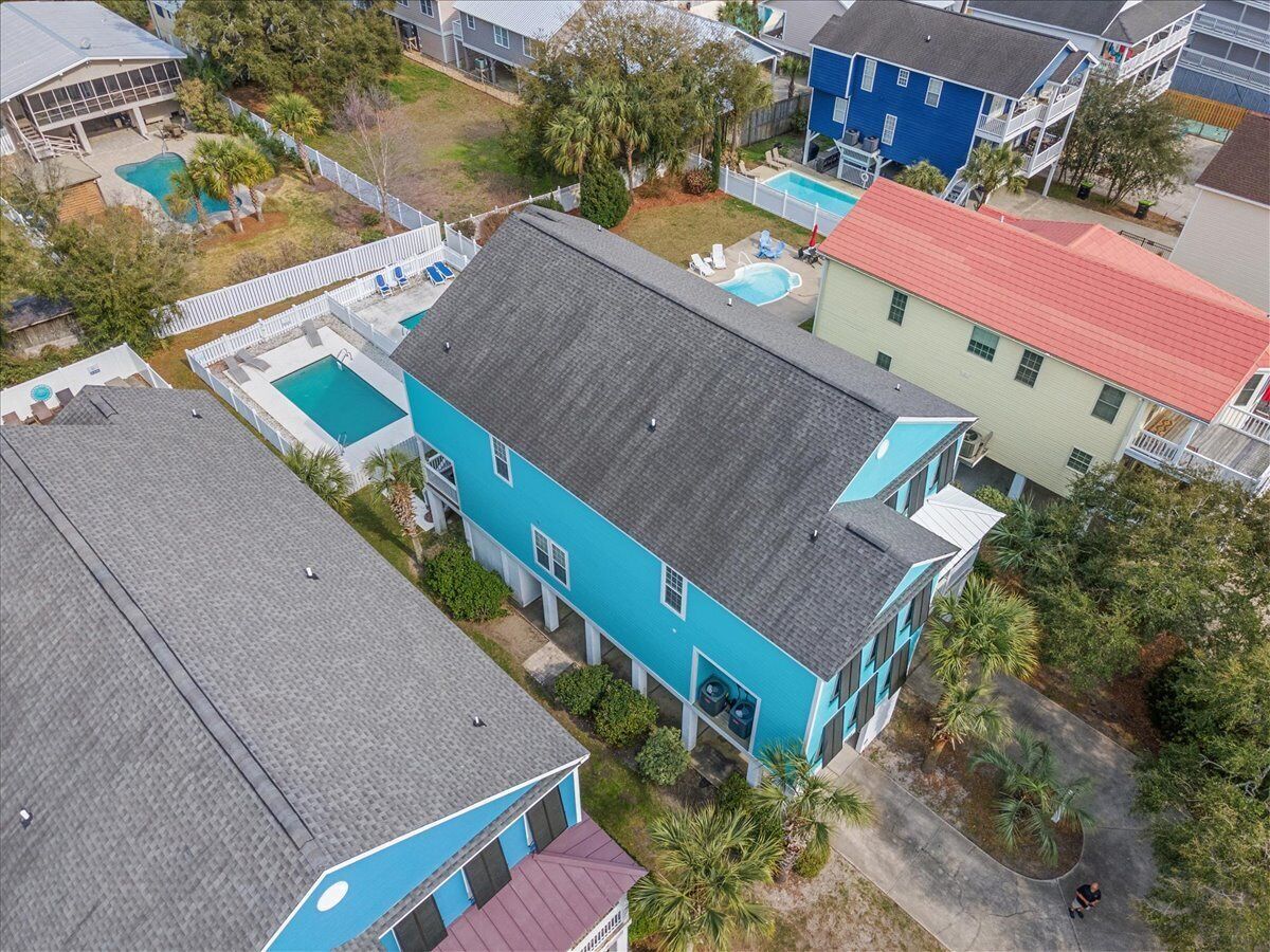 Un edificio residencial con fachada azul, techo rojo y una piscina.