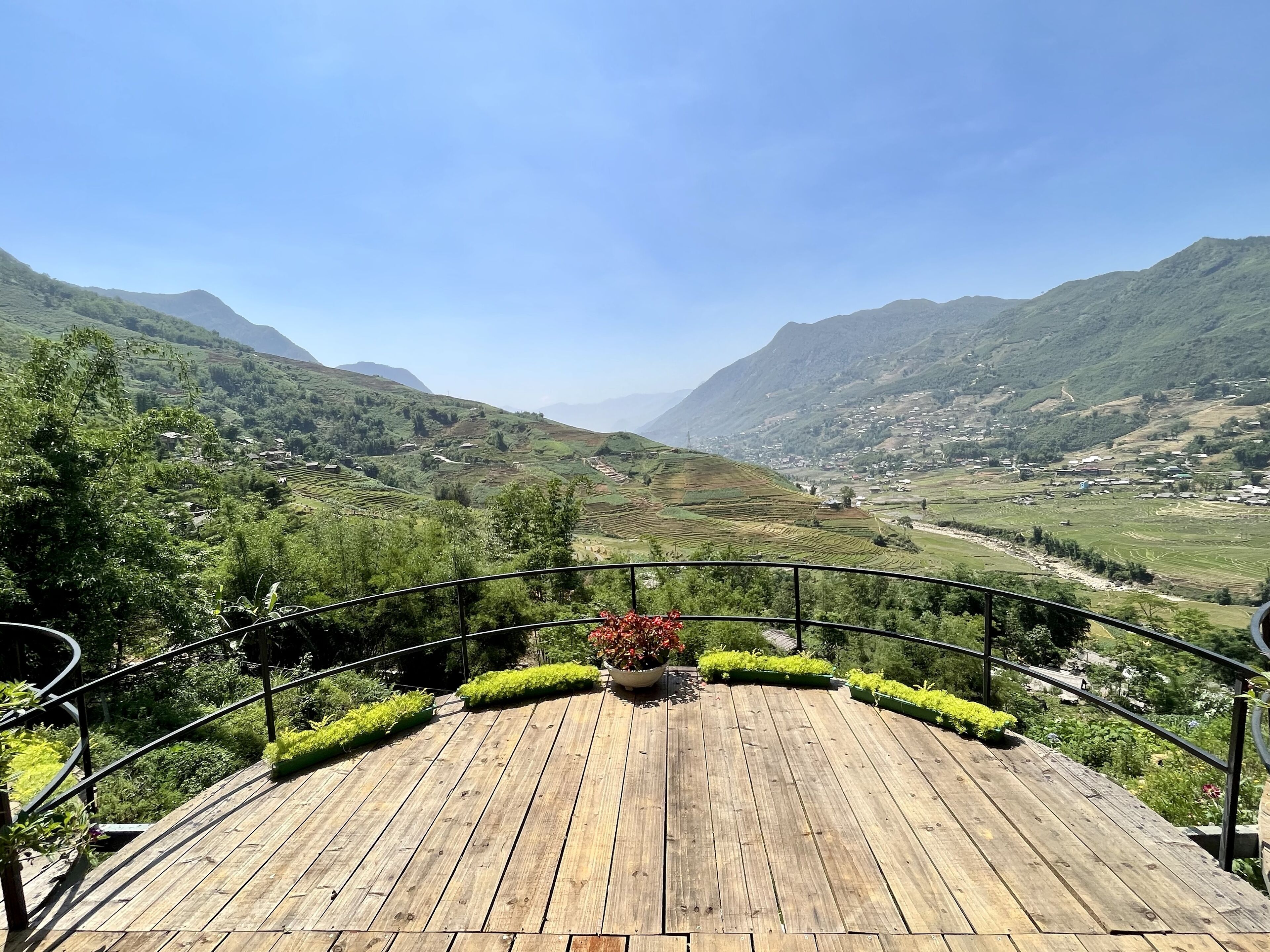 A wooden deck with a view of terraced fields and mountains.