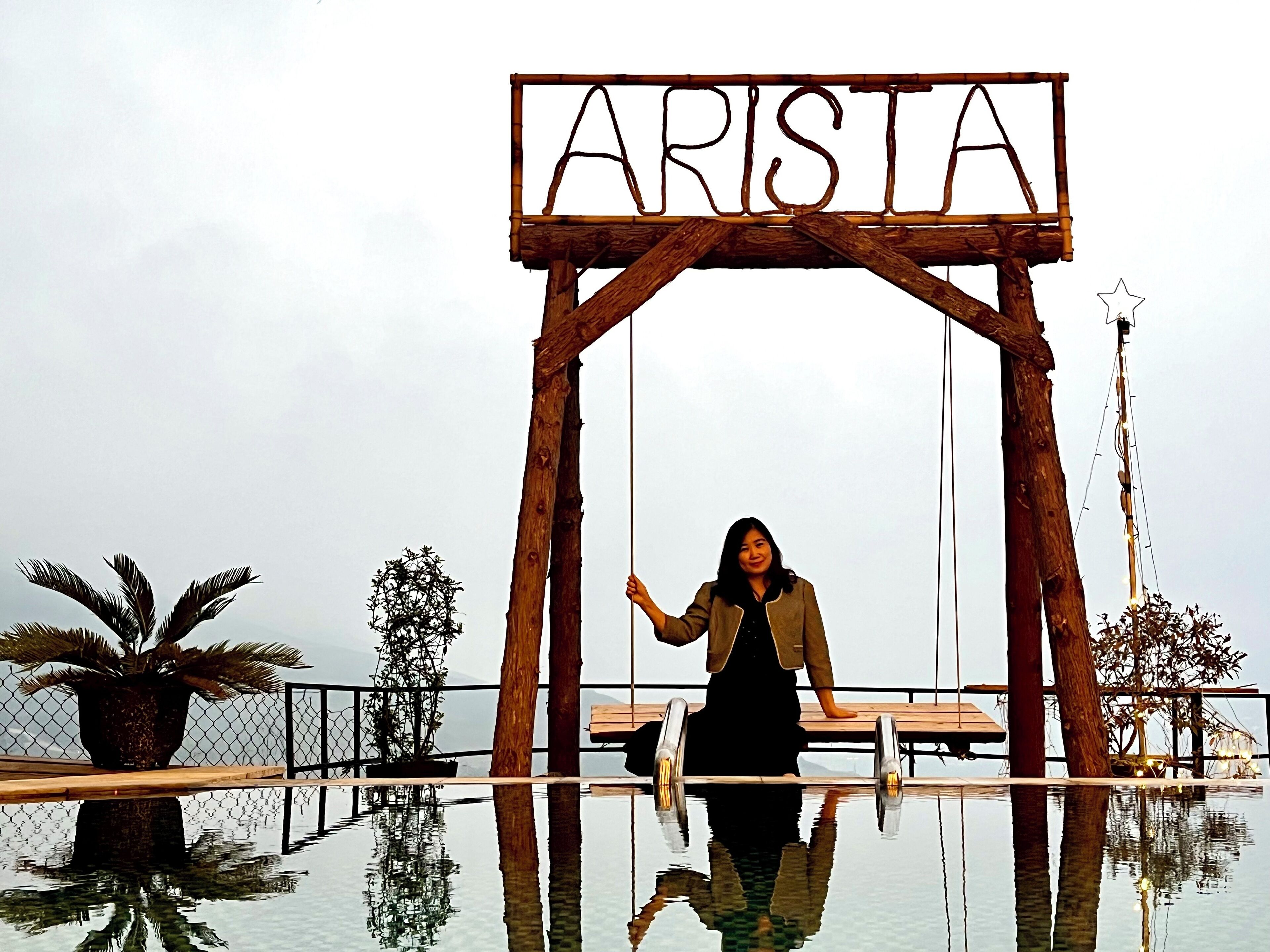 Un arco de madera con la palabra "ARISTA" y una persona de pie debajo.
