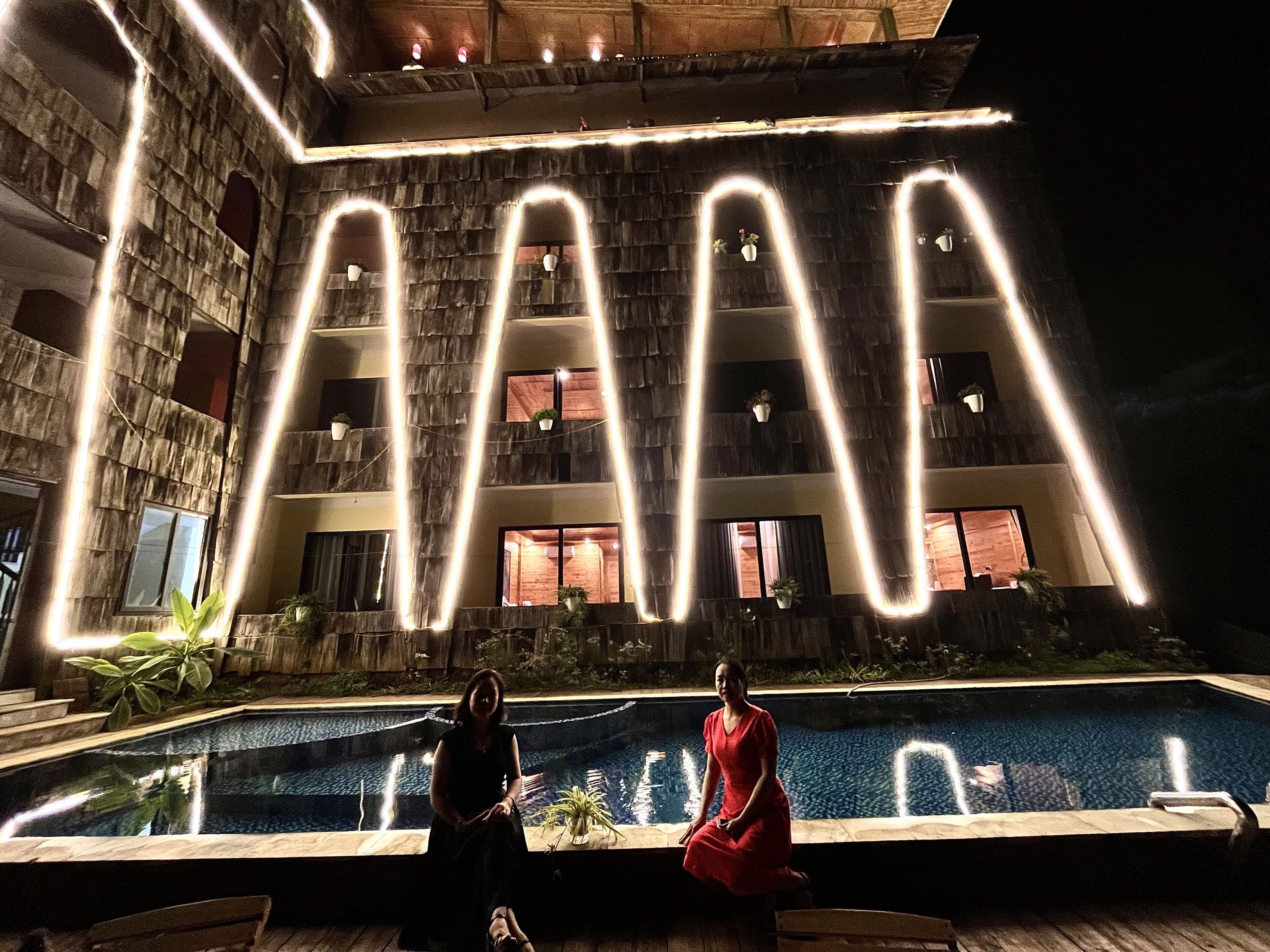 Vista de la piscina con un edificio y letras iluminadas que dicen 'LA'.