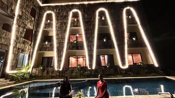 Vista de la piscina con un edificio y letras iluminadas que dicen 'LA'.