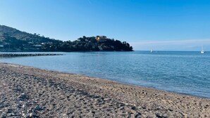 Una playa de piedras con una vista despejada de una colina con edificios.