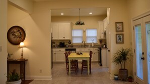 A kitchen with white cabinets, a dining table with chairs, a hanging light fixture, and a potted plant. - "Henrietta's Magnolia" Located 2 1/2 blocks from historic downtown Breaux Bridge (Breaux Bridge)