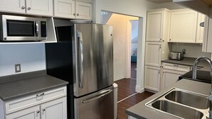 Une cuisine moderne dotée d’appareils électroménagers en acier inoxydable, de meubles blancs et d’un plancher en bois.