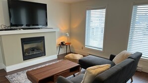 Un salon équipé d’un téléviseur à écran plat, d’une cheminée, d’un canapé et d’une table basse.
