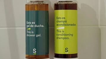 Dos botellas de gel de ducha y champú acondicionador sobre una pared de azulejos.