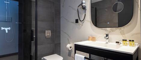A modern bathroom with a glass-enclosed shower, a toilet, a vanity with a mirror, and a towel rack.