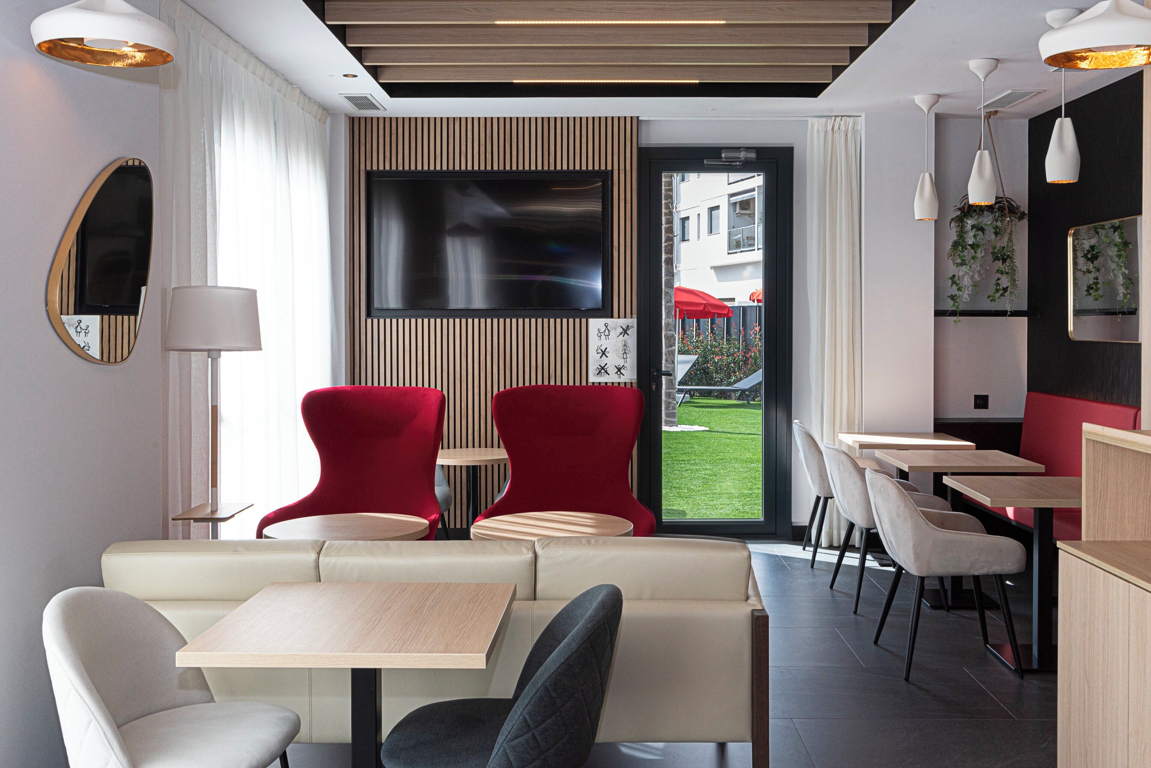 Un intérieur moderne avec des espaces aménagés pour s’asseoir, un téléviseur à écran plat et une vue sur l’extérieur.