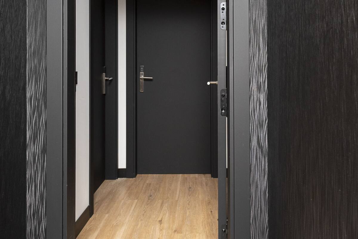 Entrada moderna de hotel com acabamento em madeira escura, placa indicando a suíte 307 e uma porta visível com puxador.