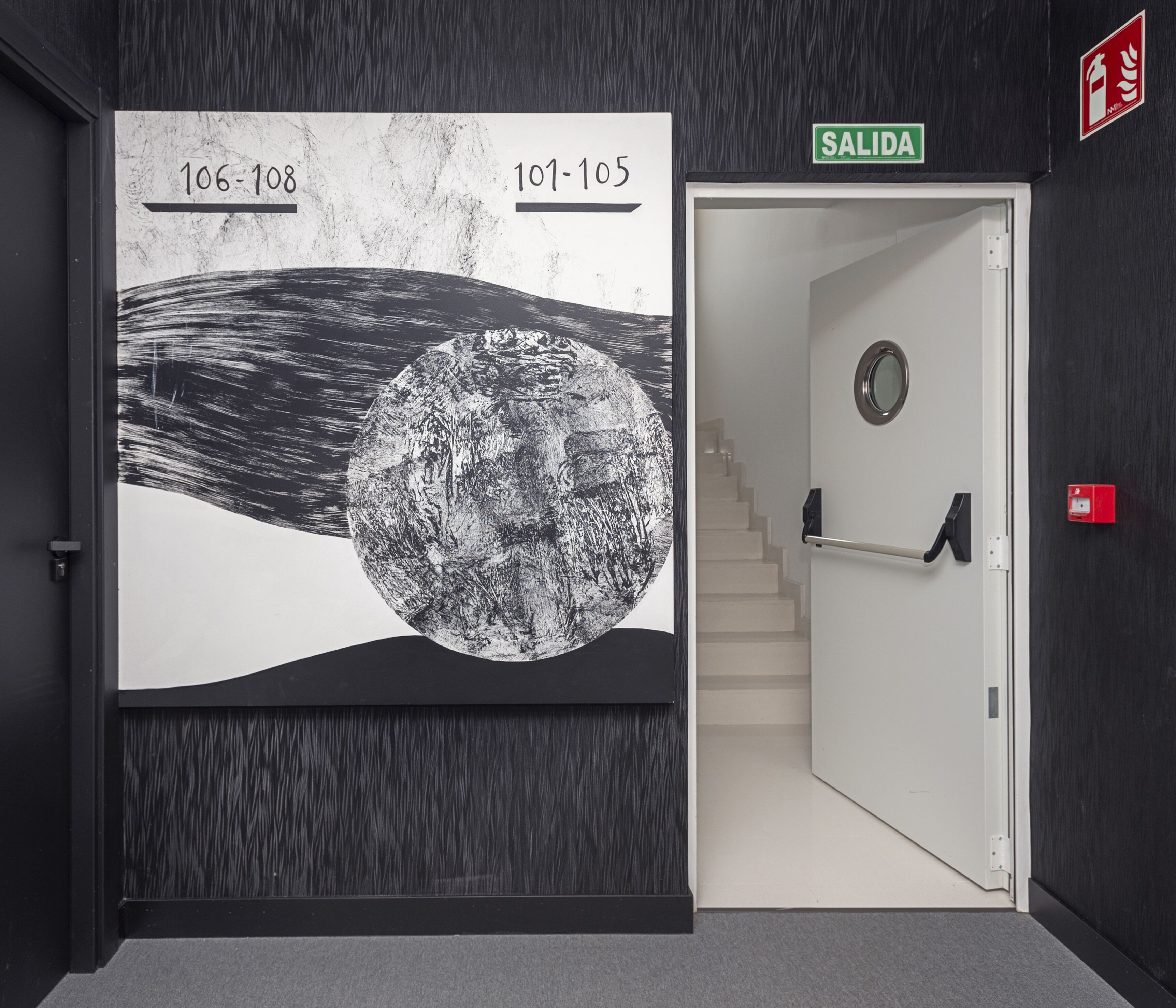 A hallway with a large wall mural depicting a moon, a staircase, and a door labeled 'SALIDA'.