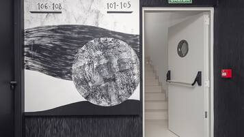 A hallway with a large wall mural depicting a moon, a staircase, and a door labeled 'SALIDA'.