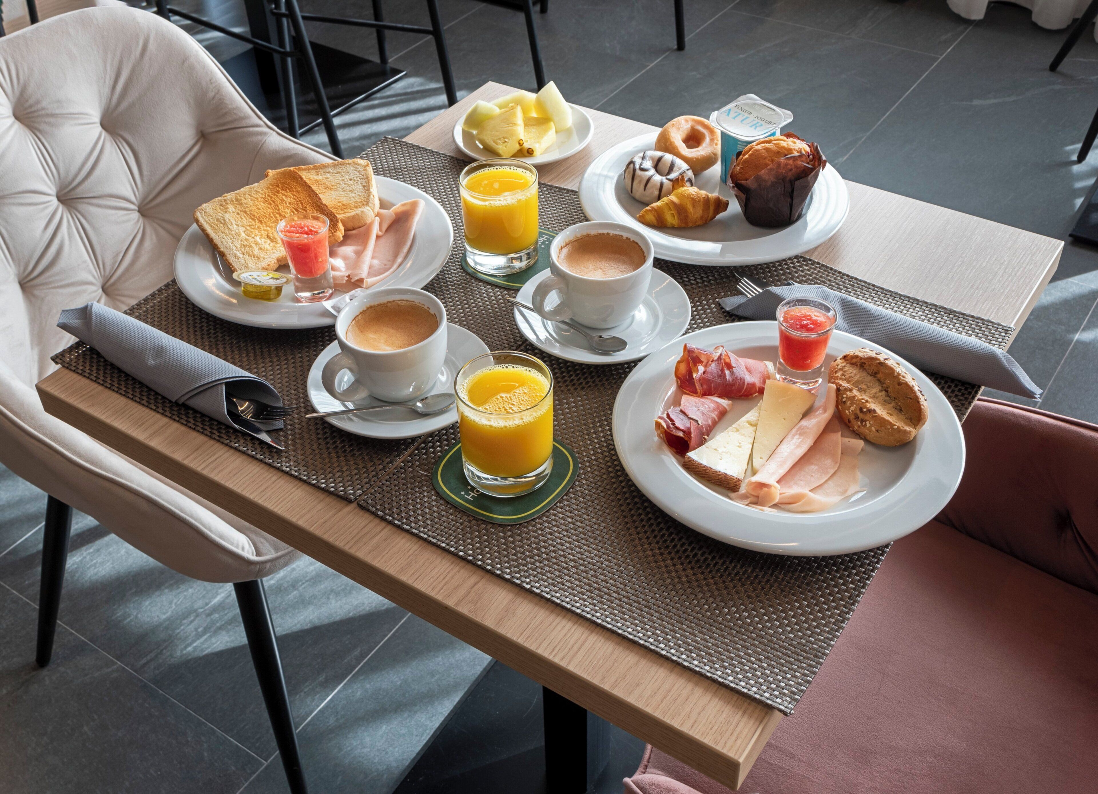 Una mesa de desayuno con tostadas, huevos, fruta, bollería y bebidas.