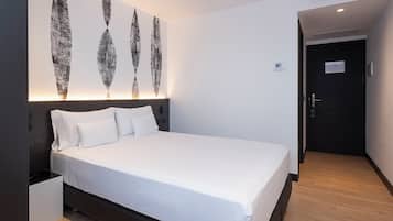 Een moderne hotelkamer met een groot bed, een hoofdbord met ingebouwde verlichting en een aan de muur hangend kunstwerk.
