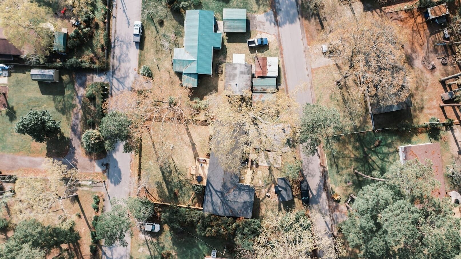 An aerial view of a residential area with multiple houses, roads, and sparse vegetation.