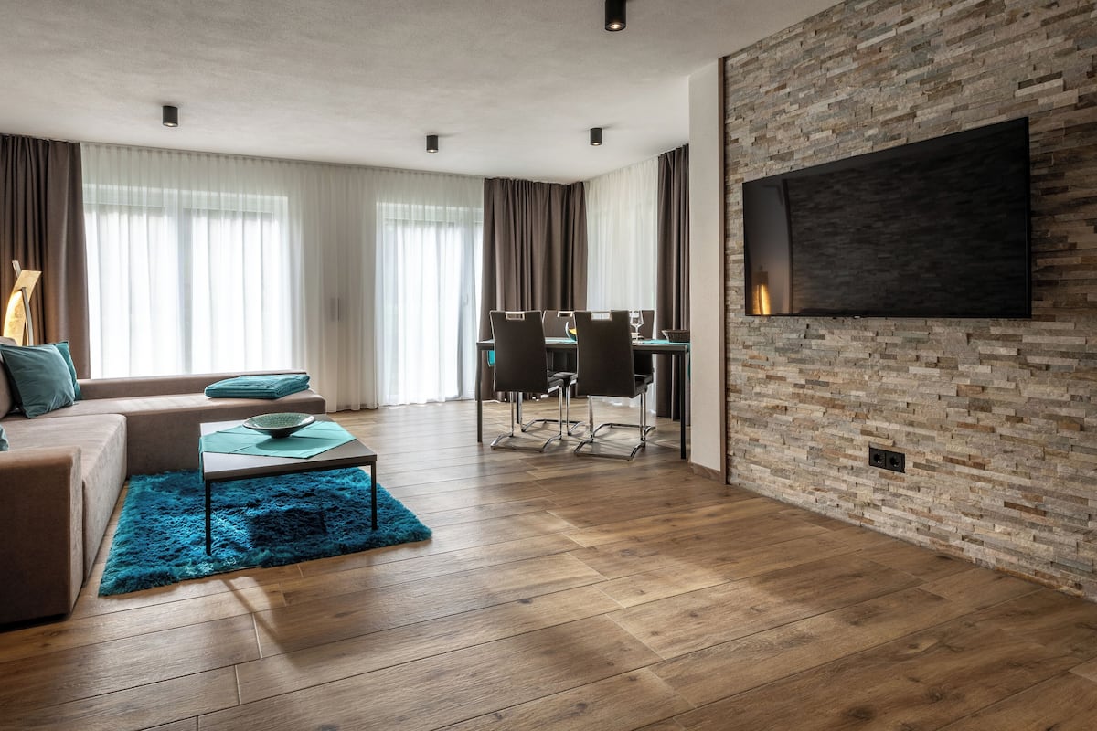 A modern living room with a sofa, coffee table, and a TV mounted on a brick wall.