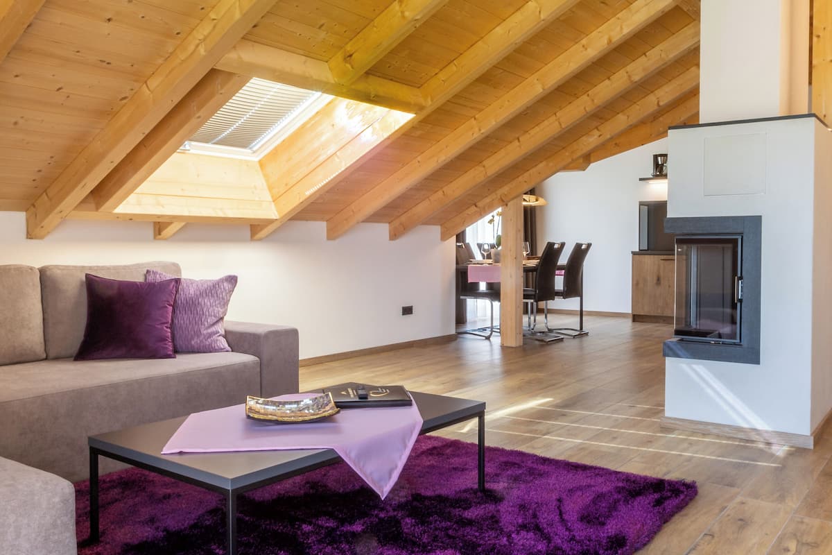 A modern loft-style living space with a sloped ceiling, a dining area, and a fireplace.