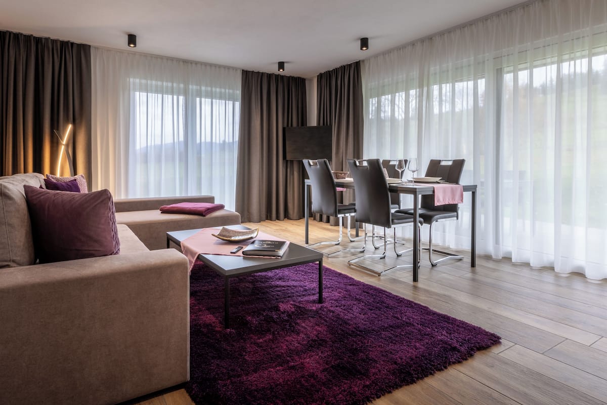 A modern living room with a sofa, a coffee table, and a dining area with chairs and a table.