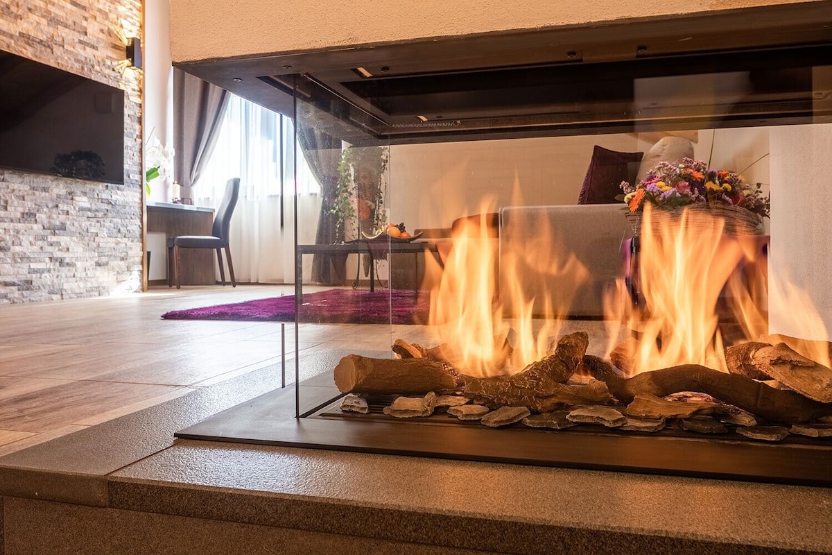 A modern living room with a glass fireplace, a sofa, and a decorative vase.