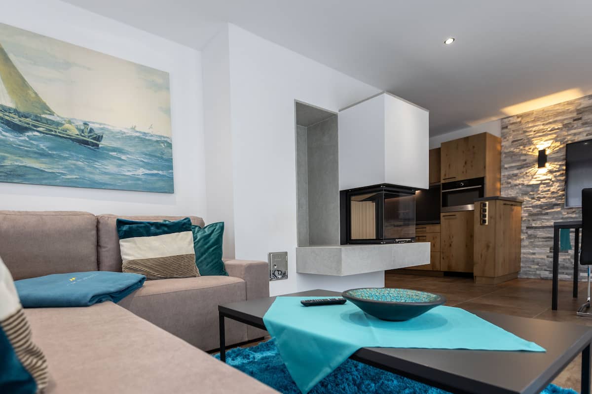 A modern living room with a sofa, a coffee table, and a painting of a sailboat.