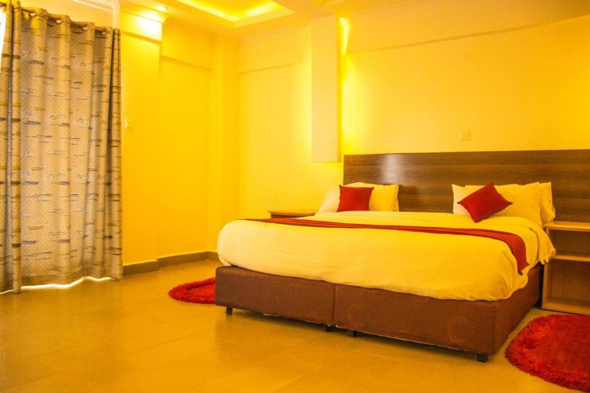 A hotel room with a large bed, a nightstand, and a red rug.