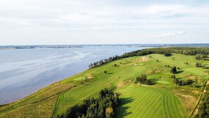 Un parcours de golf bordé d’un côté par un plan d’eau et de l’autre par une zone boisée.
