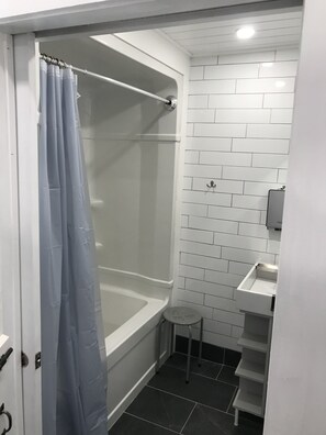 A small, modern bathroom with a shower, a toilet, and a sink. - Wild Pines Cabins (Eldon)