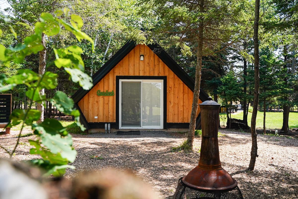 Uma cabana de madeira com porta de vidro e uma placa com a palavra 'Cottage'.