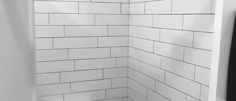 Un baño con azulejos blancos tipo metro en las paredes y un inodoro blanco.