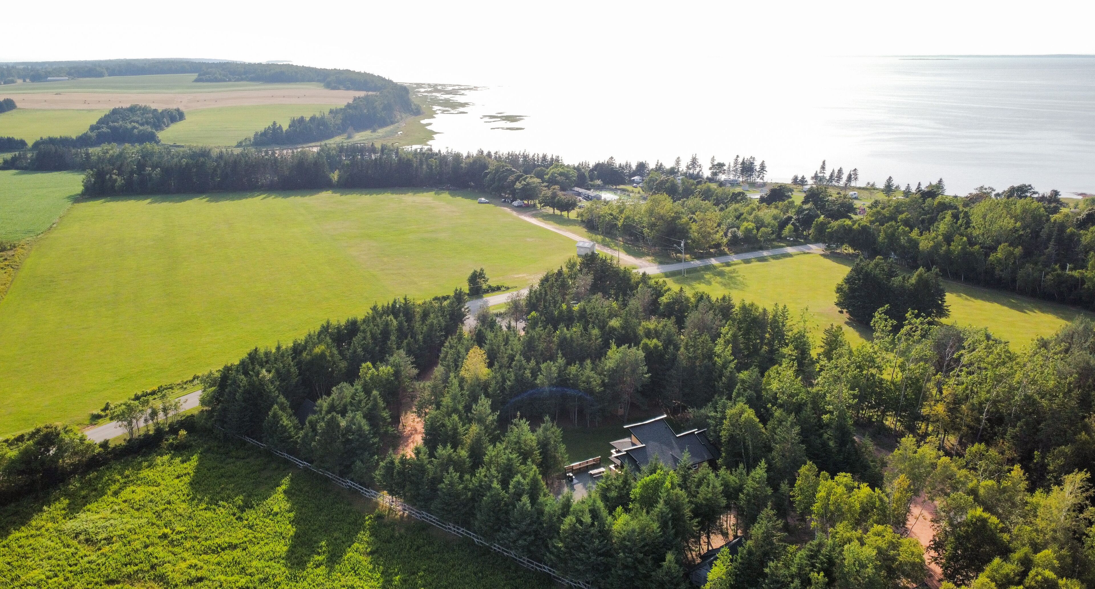 Luchtbeeld van een pand met een groot groen veld, een bebost gebied en een waterpartij.