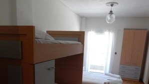 A bunk bed room with a wooden desk and wardrobe, wooden flooring, and a ceiling fan. - Baroque 10-person Apartment in Makrygialos (Pydna-Kolindros)