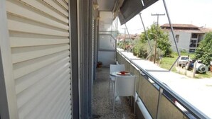 A narrow balcony with a metal railing, a small white table, and a chair. - Baroque 10-person Apartment in Makrygialos (Pydna-Kolindros)