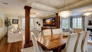A dining area with a wooden table, white chairs, and a chandelier.