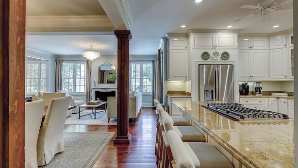 A spacious kitchen with white cabinetry, a stainless steel refrigerator, and a marble island.