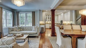 A spacious living room with a sofa, a dining table, and a kitchen in the background.
