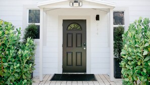 A white house with a dark green door, a small porch, and a mailbox. - Cozy - full kitchen & 10ft island - 1.2G Wifi (Fort Lauderdale)